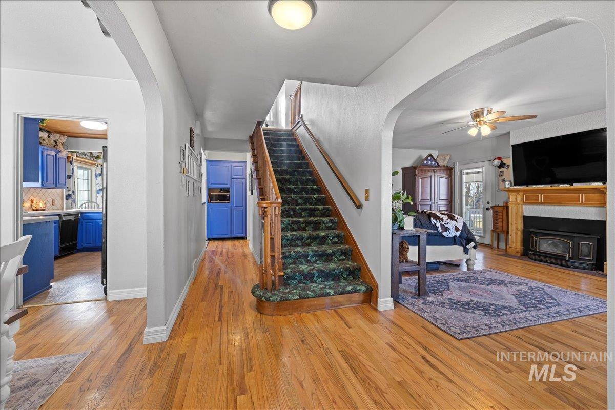 Stairway featuring arched walkways, wood-type flooring, and a fireplace