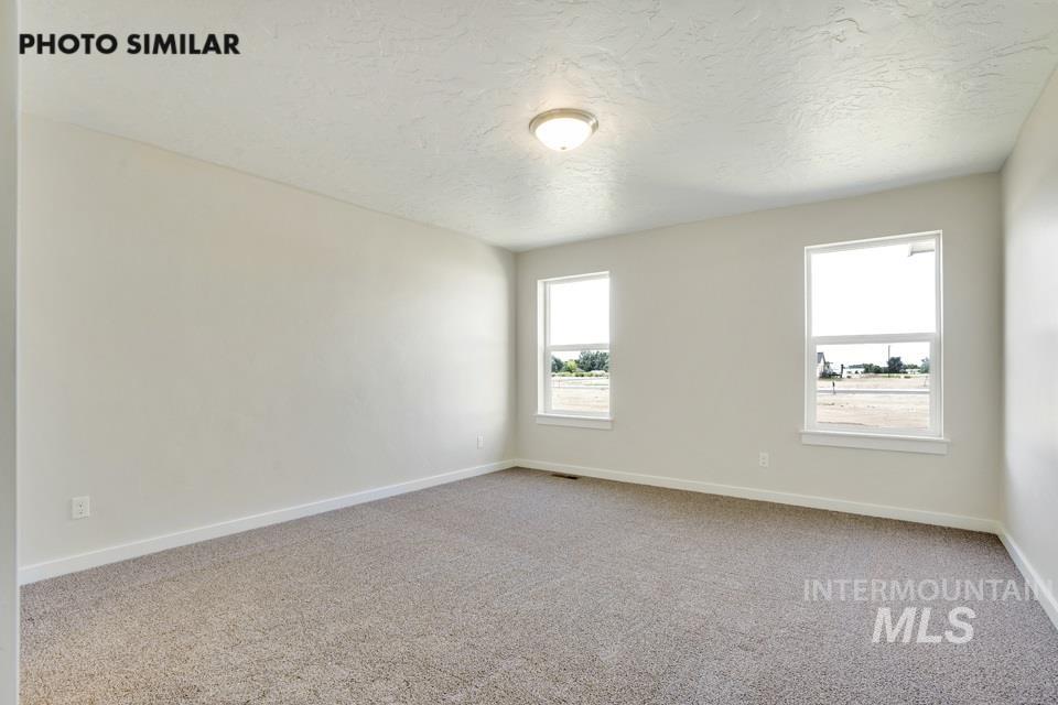 Empty room featuring light carpet and a textured ceiling