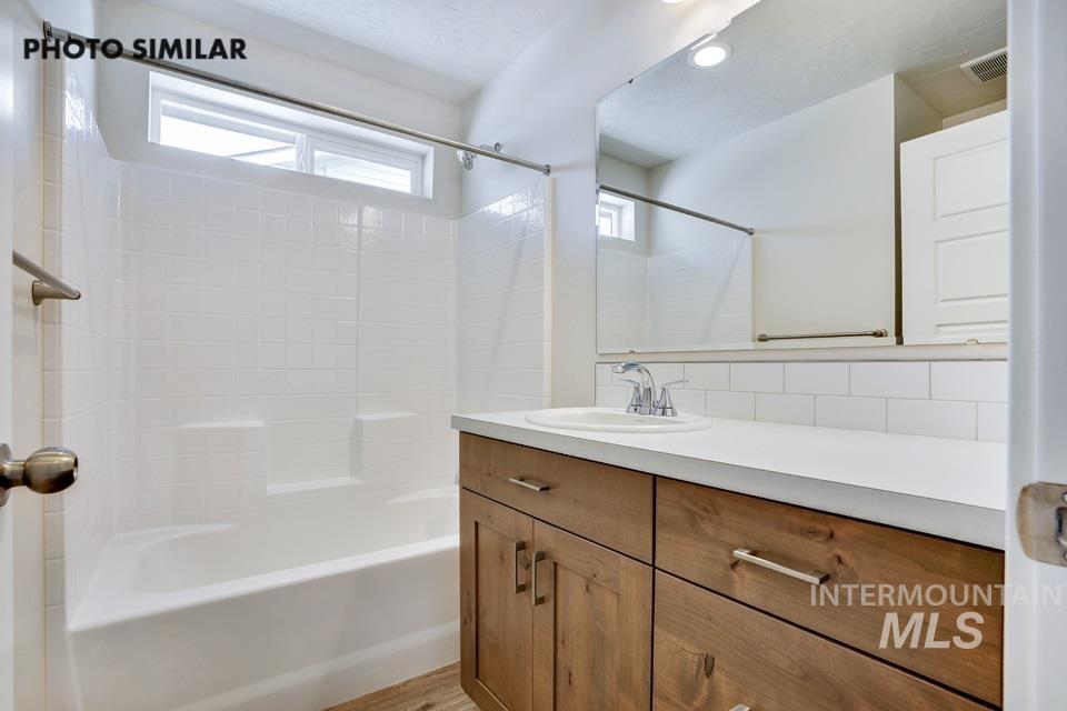 Full bathroom with vanity, shower / bath combination, light wood-style floors, recessed lighting, and decorative backsplash