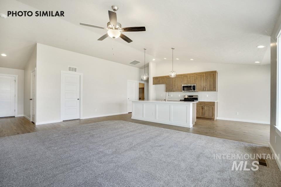 Unfurnished living room with vaulted ceiling, light colored carpet, ceiling fan, light wood-type flooring, and recessed lighting