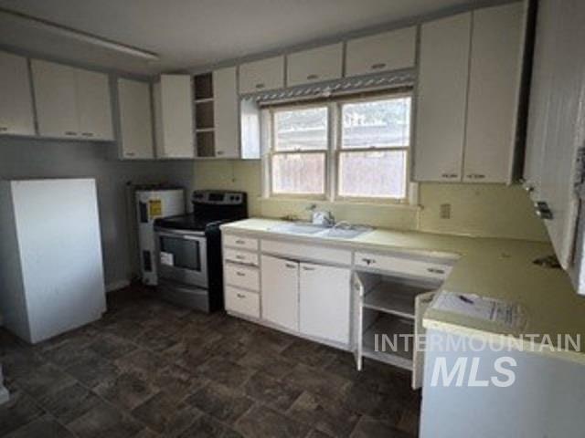 Kitchen featuring freestanding refrigerator, electric stove, light countertops, white cabinetry, and open shelves