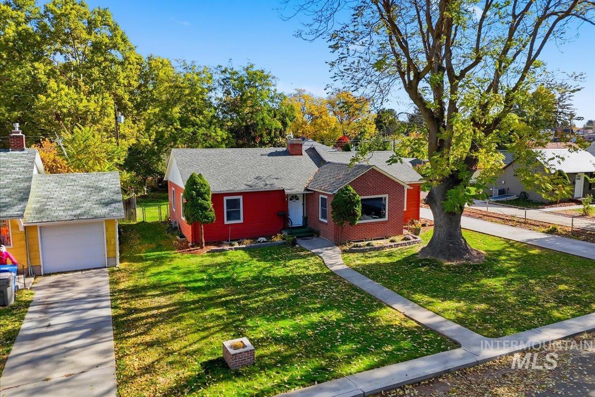 View of front of house with a chimney, a front yard, and a garage