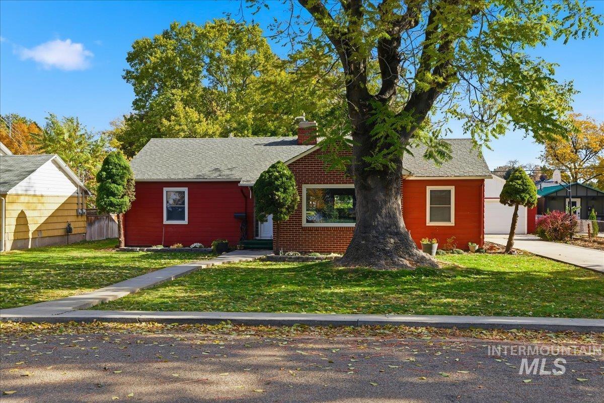View of front of property with a front lawn, a chimney, and roof with shingles