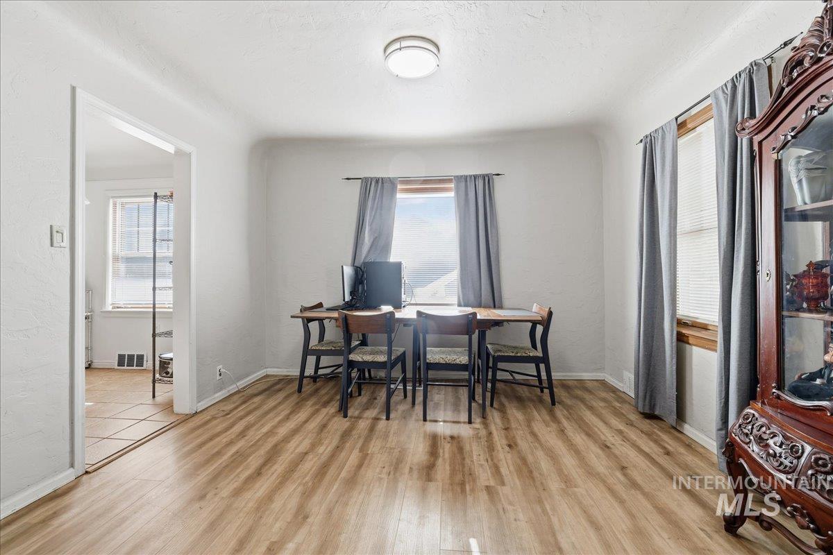 Dining area with an office area, light wood-style floors, and a textured wall
