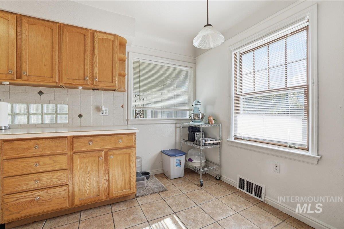 Kitchen featuring decorative backsplash, light tile patterned floors, and hanging light fixtures