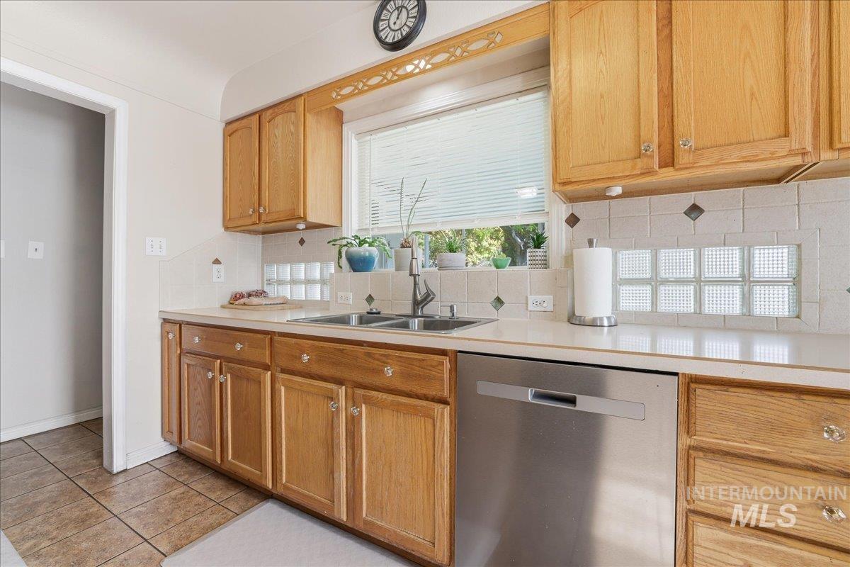 Kitchen featuring dishwasher, decorative backsplash, light countertops, and light tile patterned floors