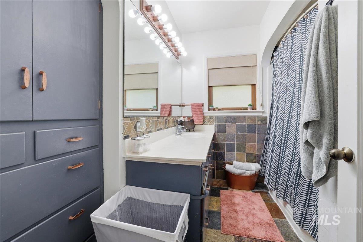 Full bathroom featuring vanity, tile walls, a shower with curtain, and tile patterned floors