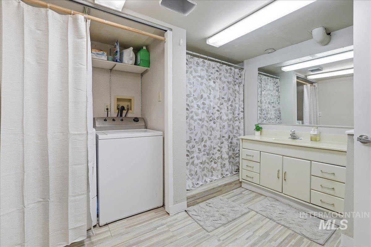 Full bath with washer / dryer, a stall shower, vanity, and light wood-type flooring