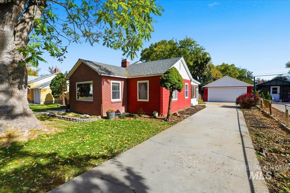 View of property exterior featuring an outdoor structure, a detached garage, a chimney, and a lawn
