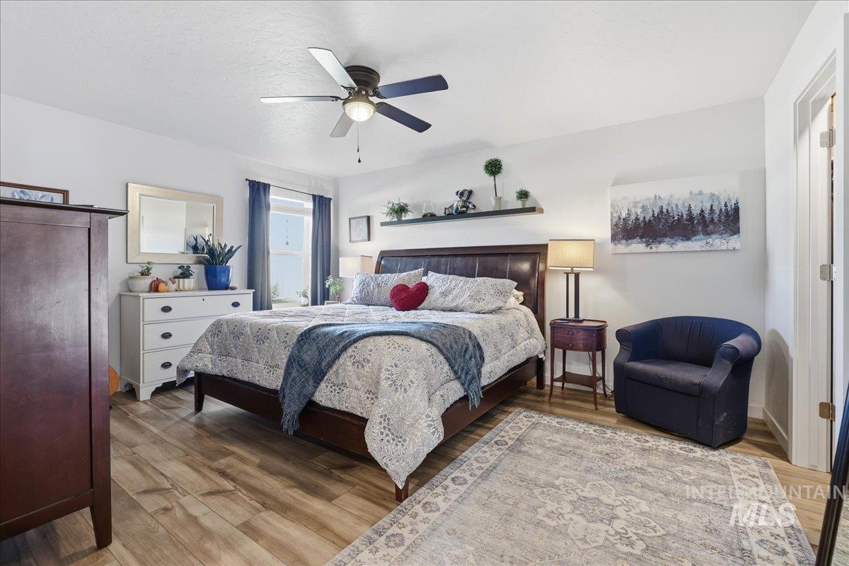 Bedroom featuring light wood finished floors, ceiling fan, and a textured ceiling