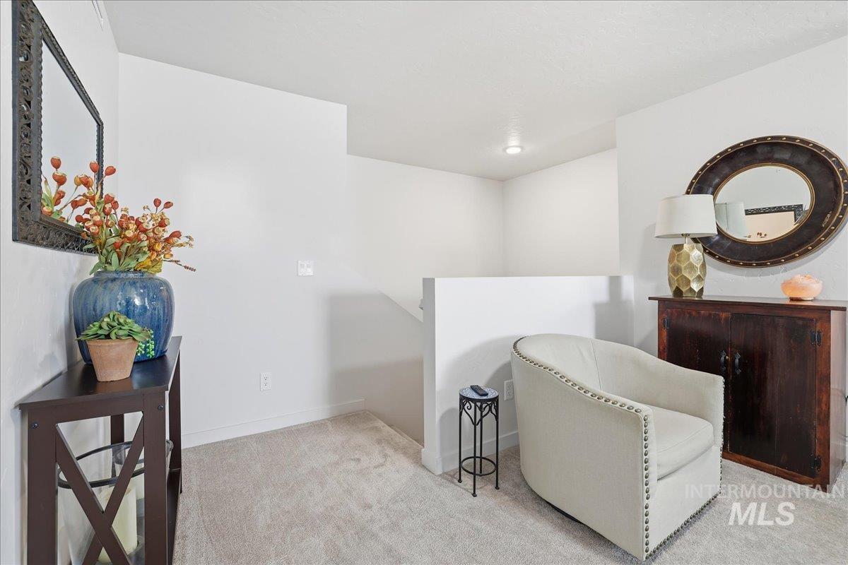 Living area featuring an upstairs landing and light colored carpet