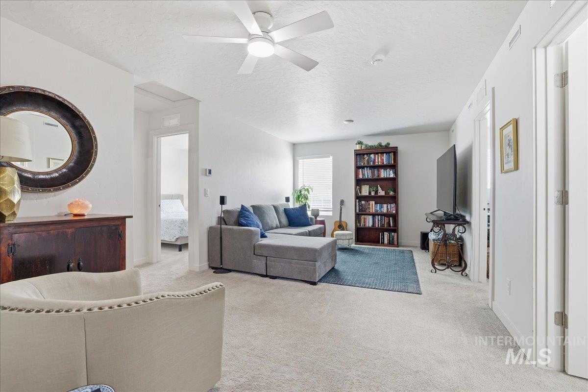 Carpeted living room with a textured ceiling and a ceiling fan