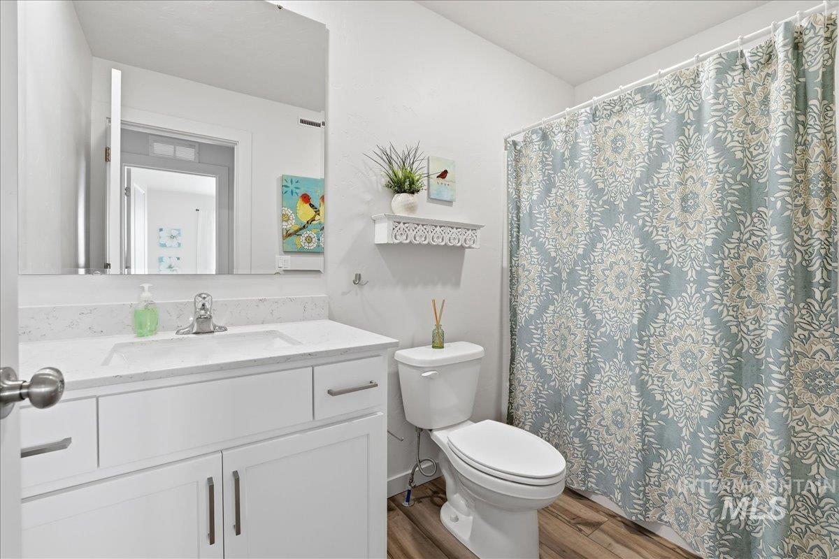 Bathroom featuring curtained shower, vanity, and wood finished floors