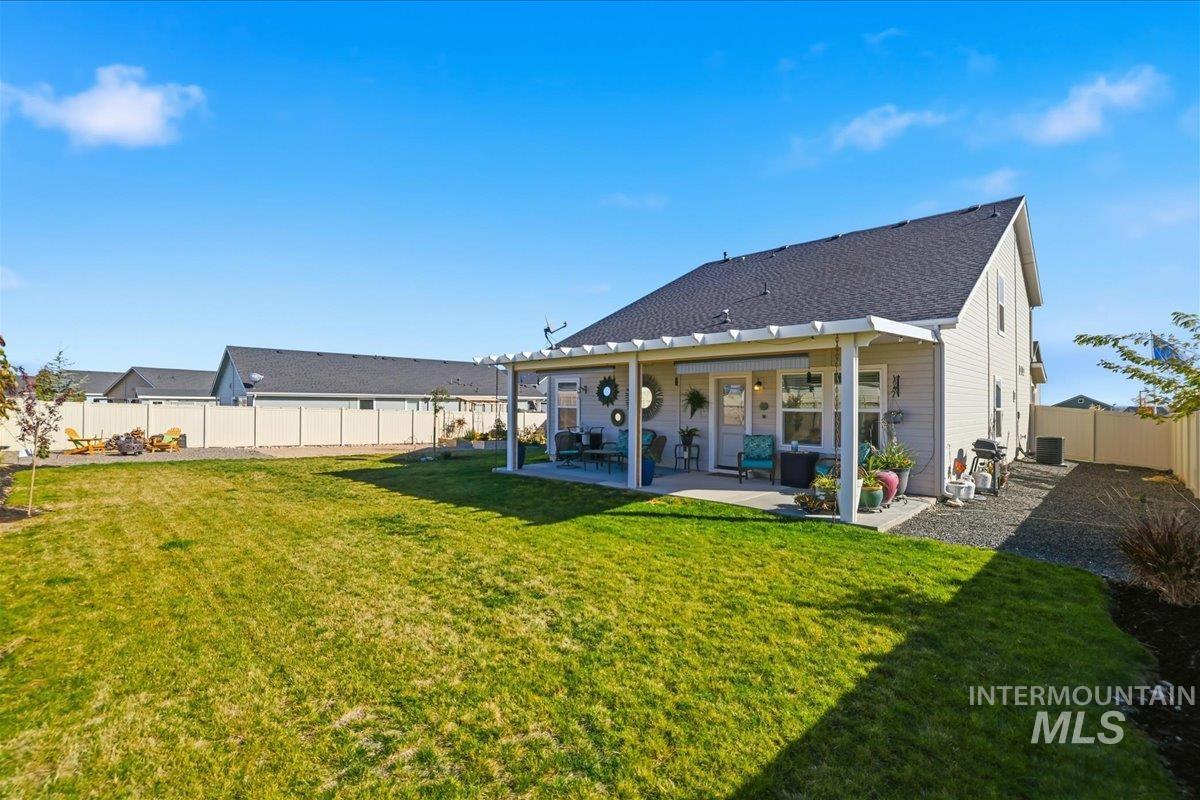 Rear view of house featuring a fenced backyard, a patio, and roof with shingles