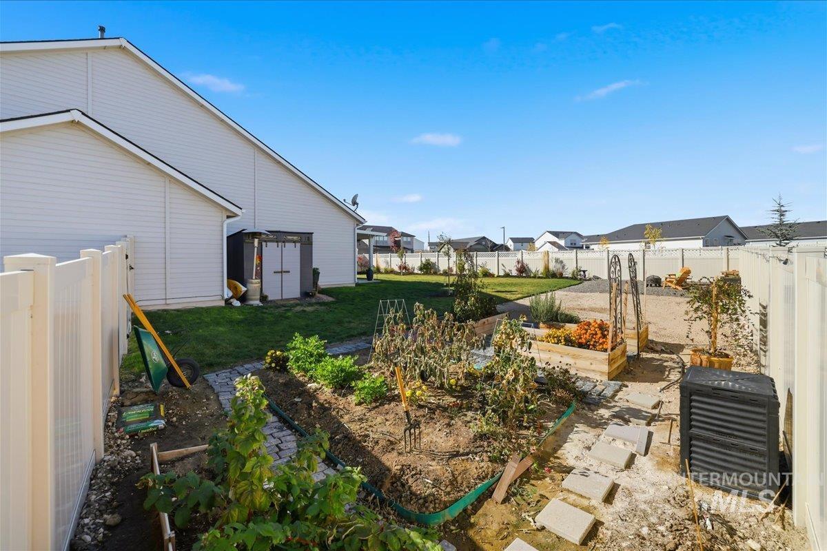 Fenced backyard featuring a garden, a residential view, and a shed