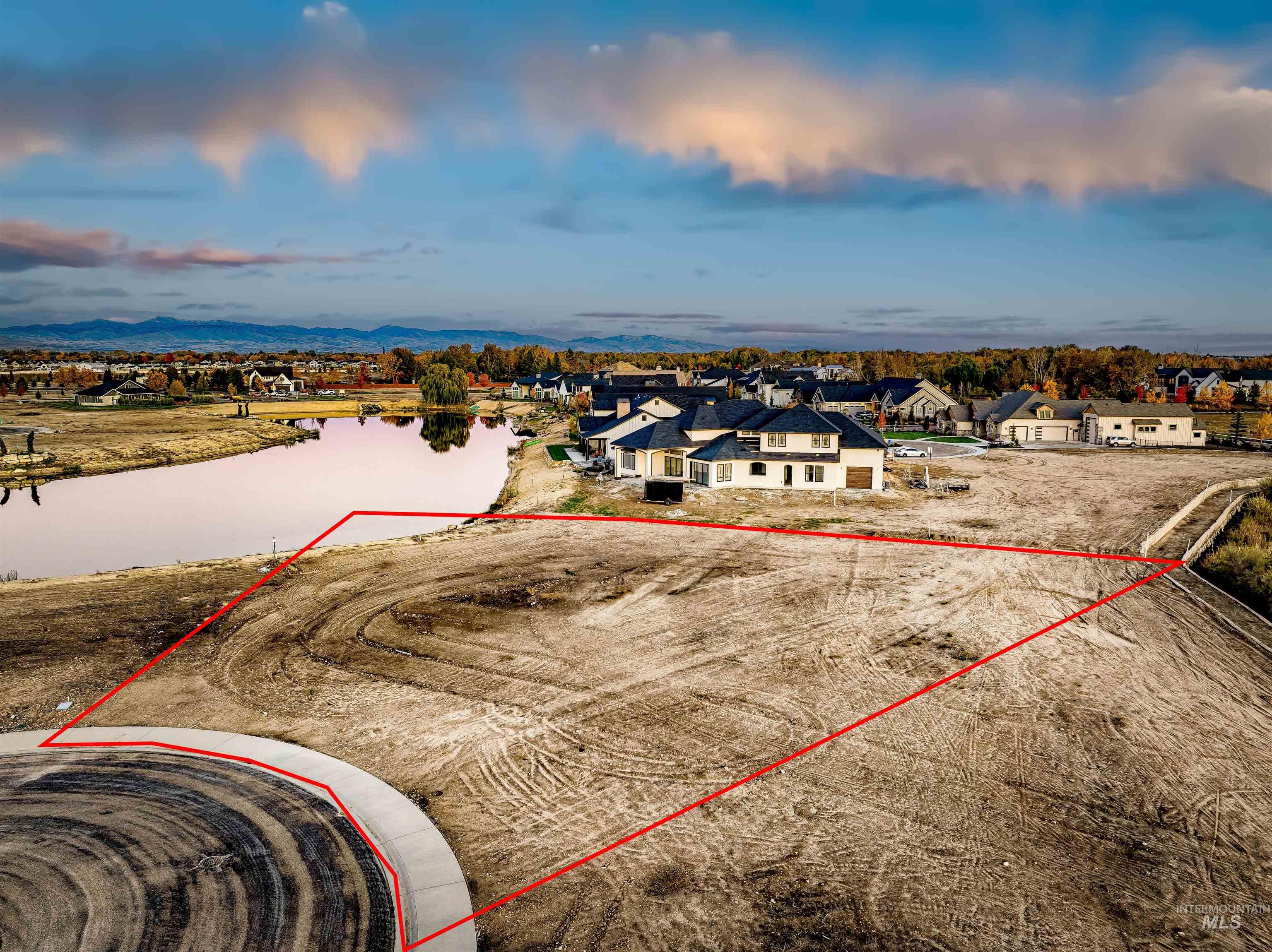 Aerial perspective of suburban area with property parcel outlined and a nearby body of water