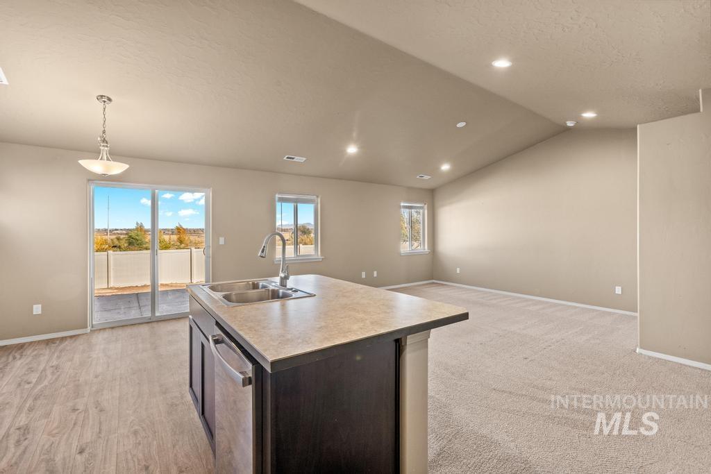 Kitchen with dark brown cabinets, open floor plan, a textured ceiling, a kitchen island with sink, and light countertops