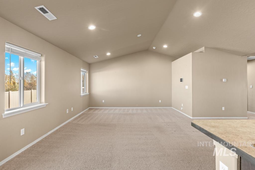 Unfurnished room with lofted ceiling, light carpet, and recessed lighting