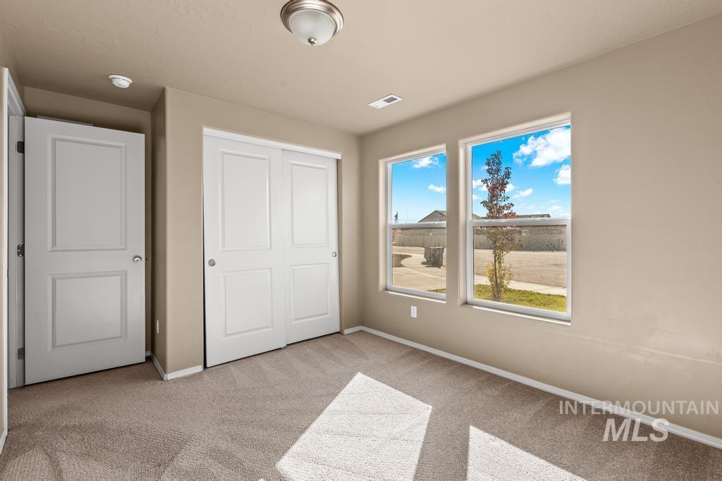 Unfurnished bedroom with light carpet and a closet