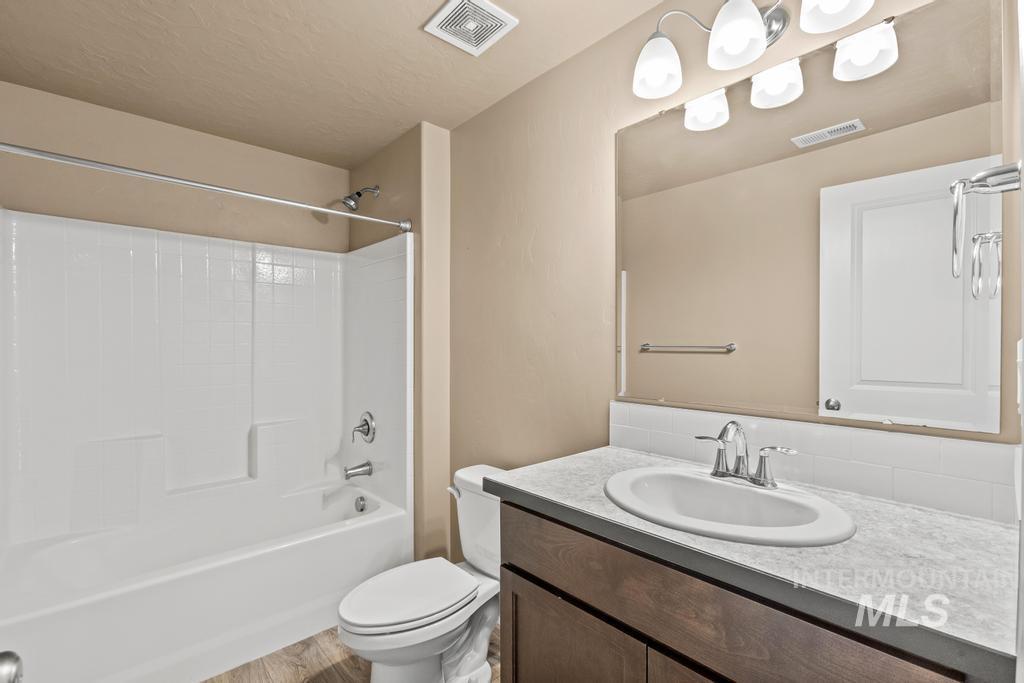 Bathroom featuring shower / bath combination, vanity, light wood finished floors, and a textured ceiling