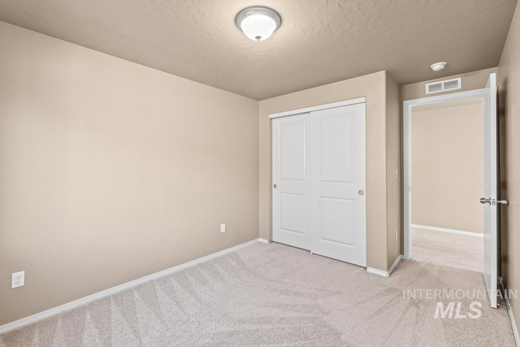 Unfurnished bedroom with light carpet, a textured ceiling, and a closet