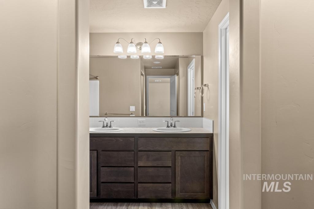 Bathroom with double vanity, a shower with curtain, and wood finished floors