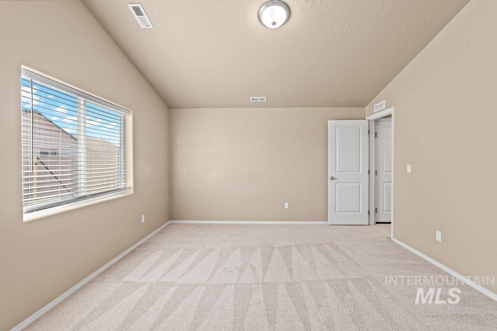 Unfurnished room with light carpet and lofted ceiling