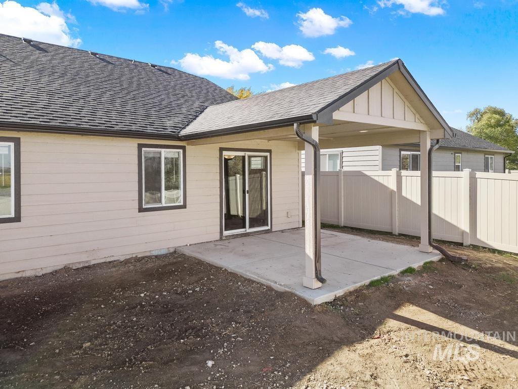 Back of property featuring roof with shingles, a patio area, and board and batten siding