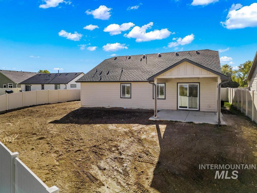 Back of property with board and batten siding, a patio, a fenced backyard, and roof with shingles