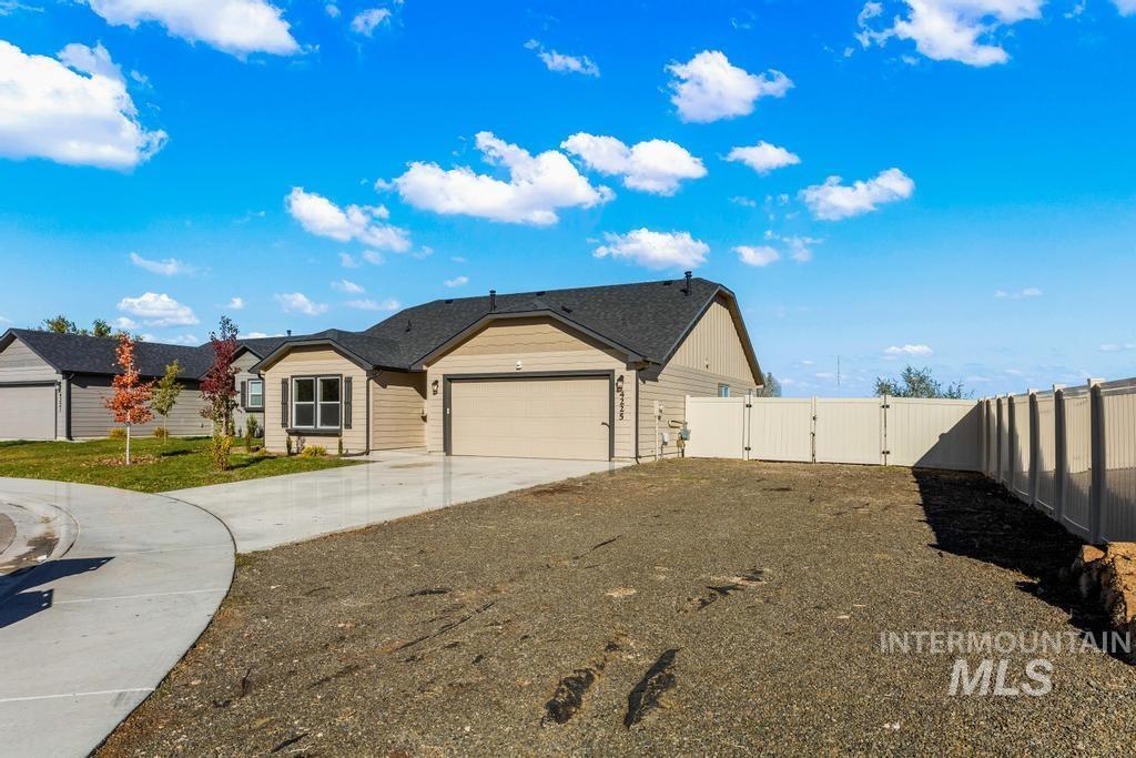 View of side of property featuring a gate, concrete driveway, and a garage