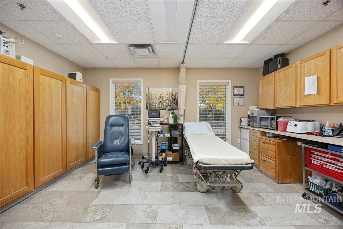 Office area with healthy amount of natural light, a paneled ceiling, and light stone finish flooring