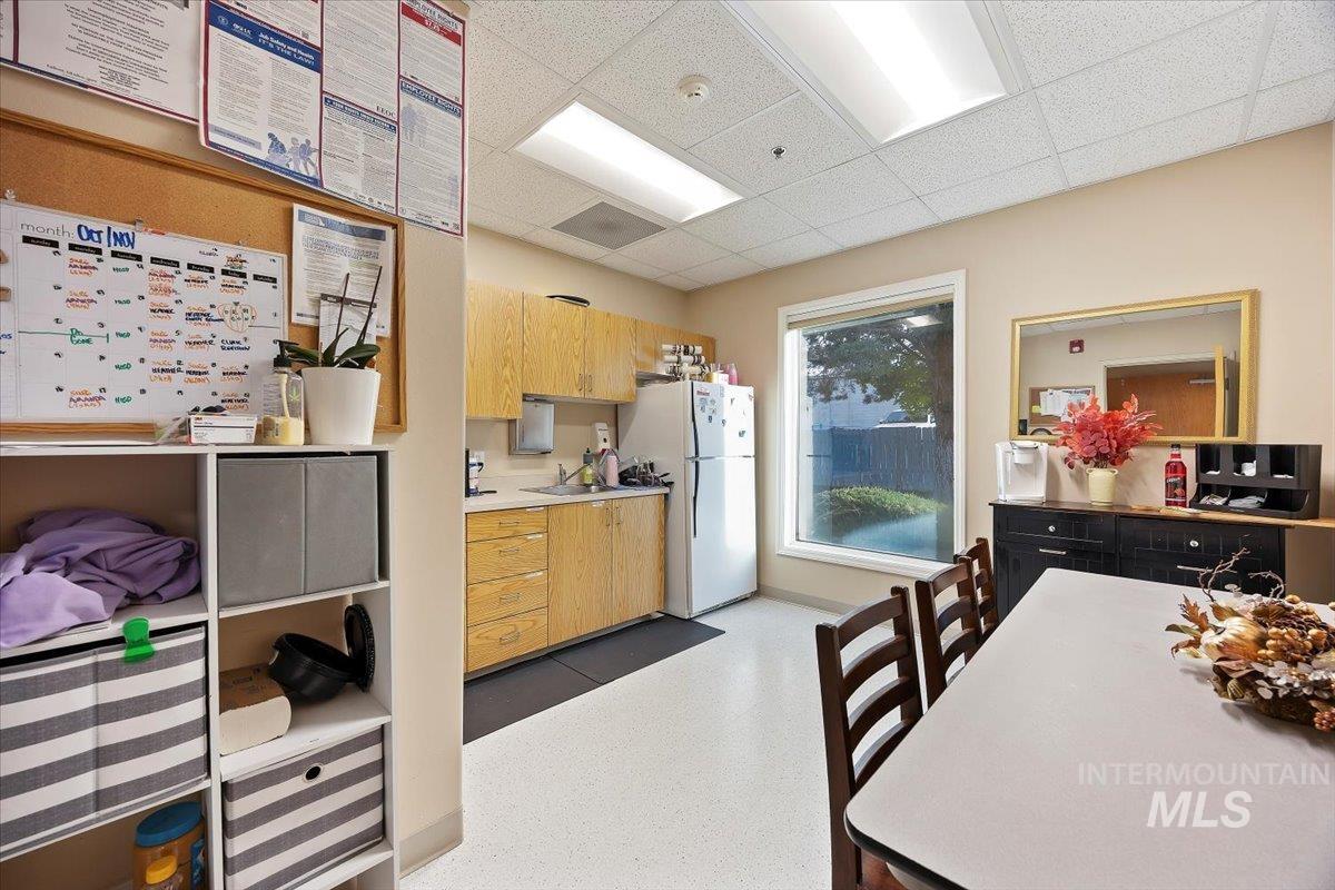 Kitchen featuring light countertops, freestanding refrigerator, light brown cabinets, and a paneled ceiling