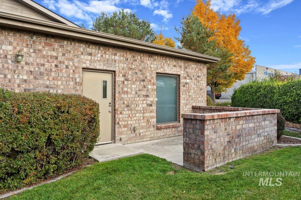 View of exterior entry featuring brick siding and a lawn
