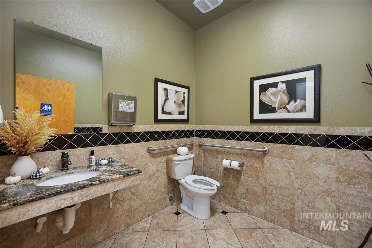 Half bathroom with tile walls and a wainscoted wall