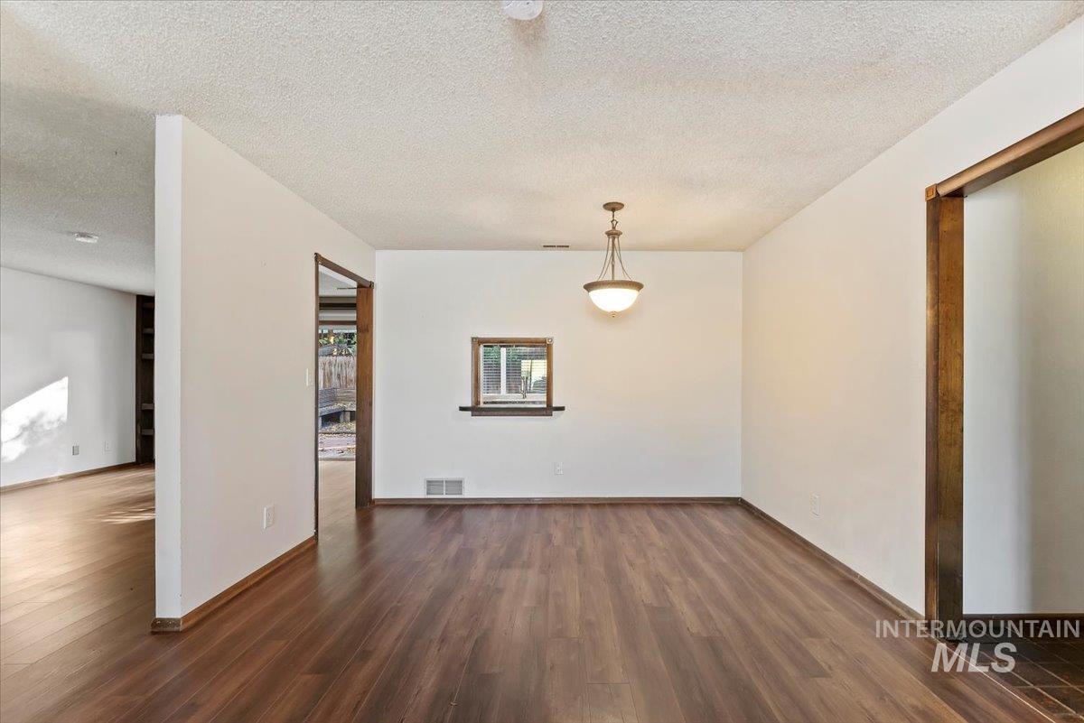 Unfurnished dining area with a textured ceiling and dark wood-type flooring
