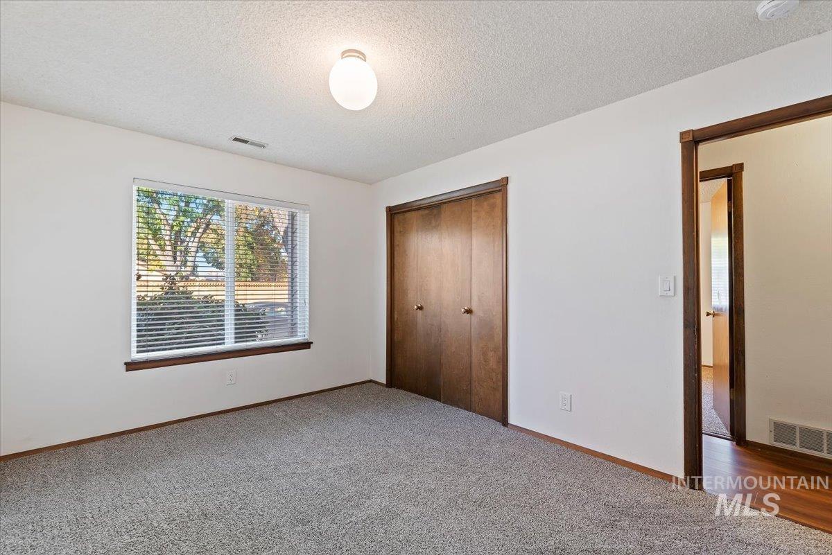 Unfurnished bedroom featuring a textured ceiling, carpet floors, and a closet