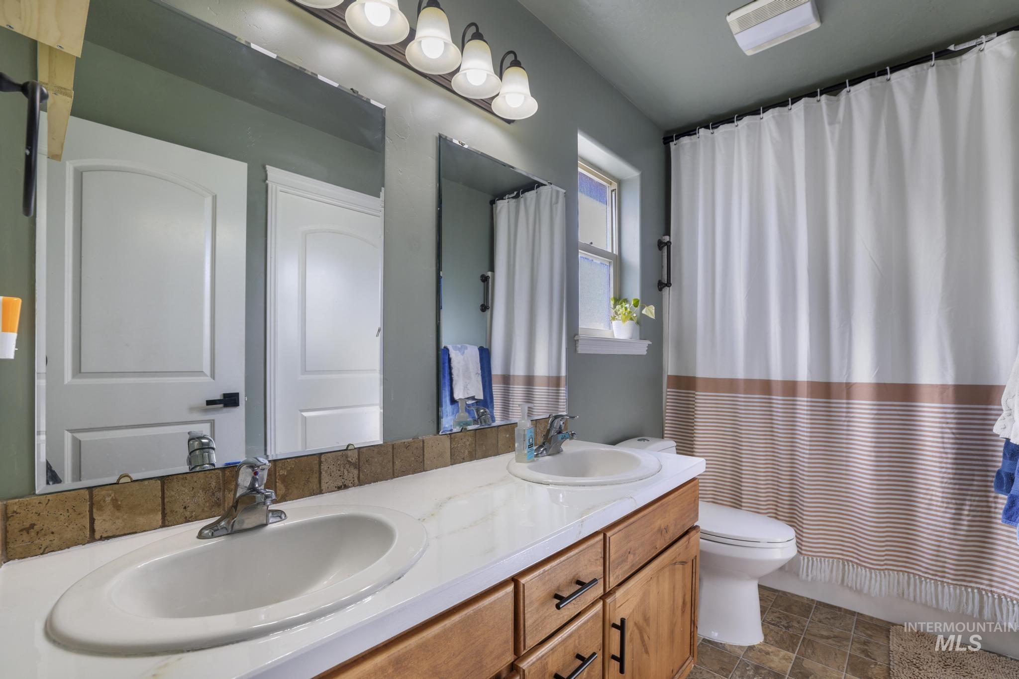 Bathroom featuring double vanity and shower / bath combination with curtain