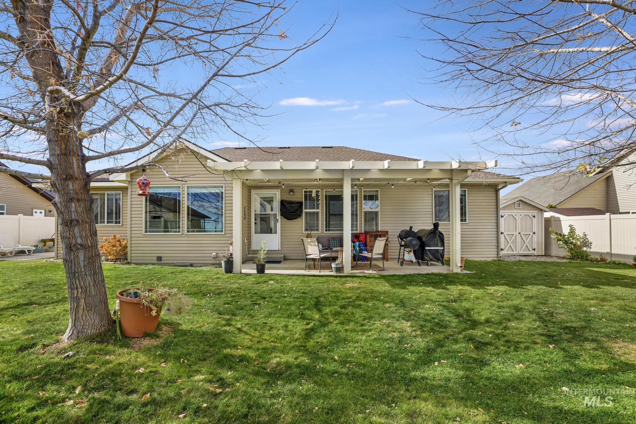 Back of property with a storage shed, roof with shingles, and a patio
