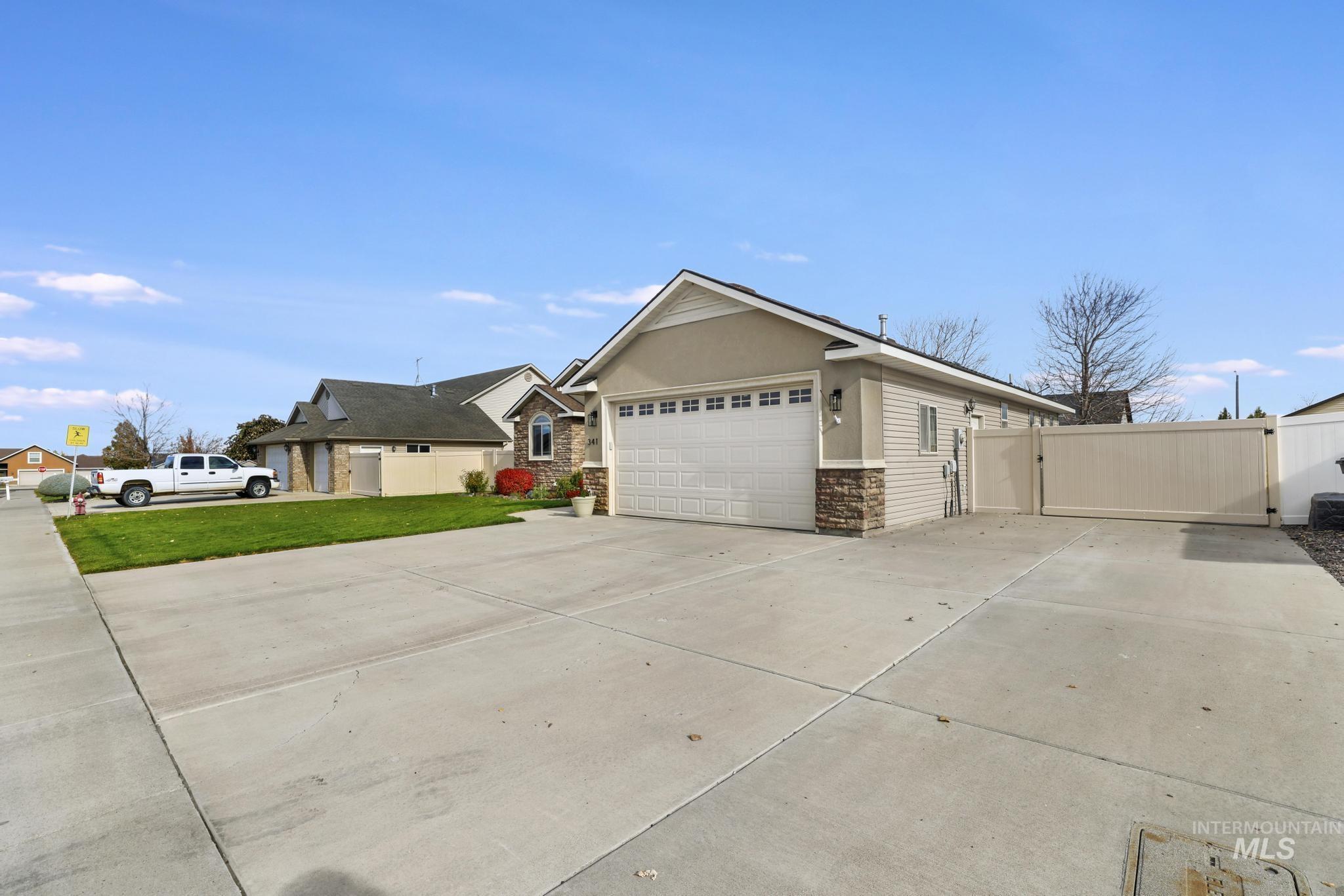 View of side of property with a gate, driveway, stone siding, and stucco siding