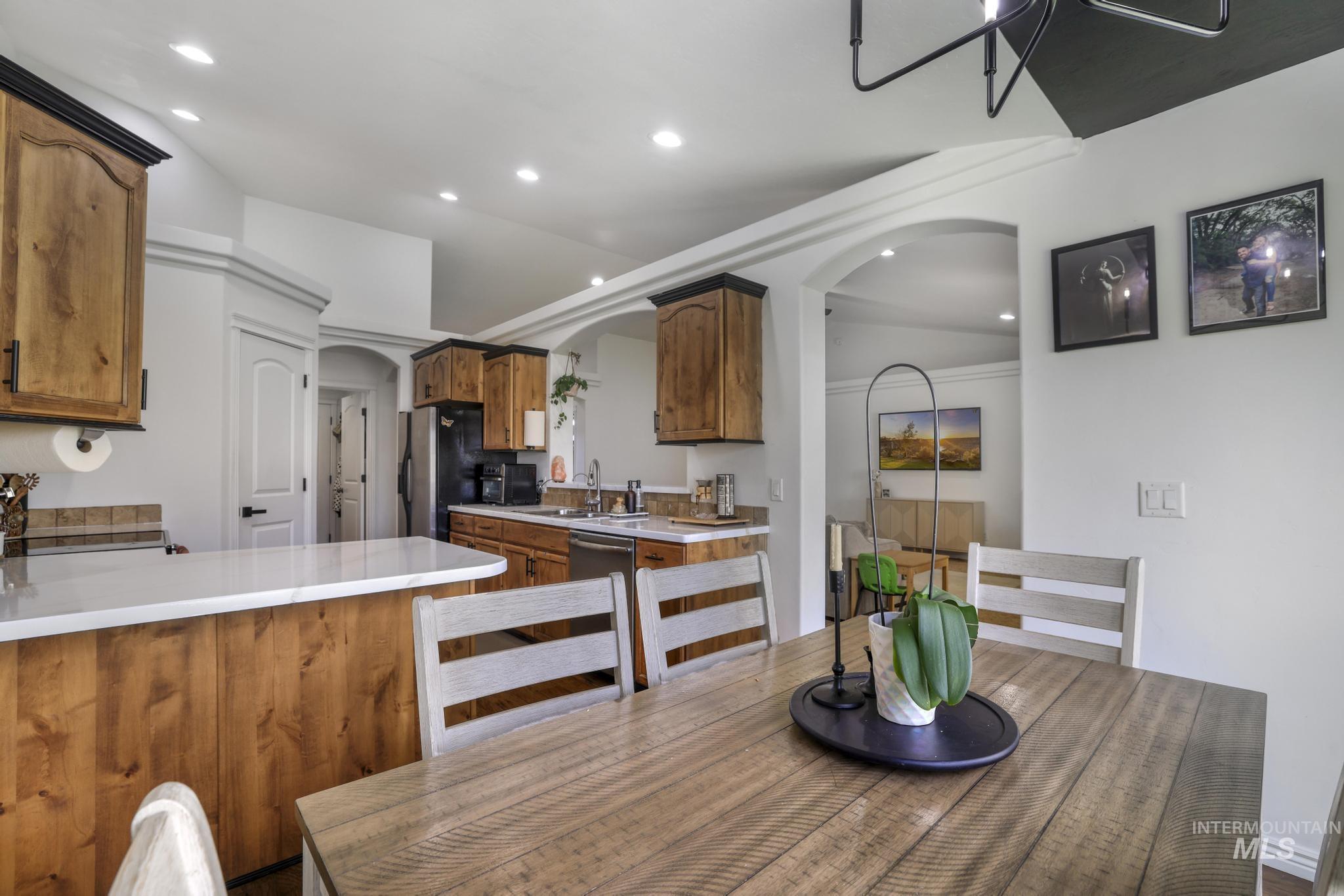 Dining space with arched walkways, recessed lighting, and vaulted ceiling