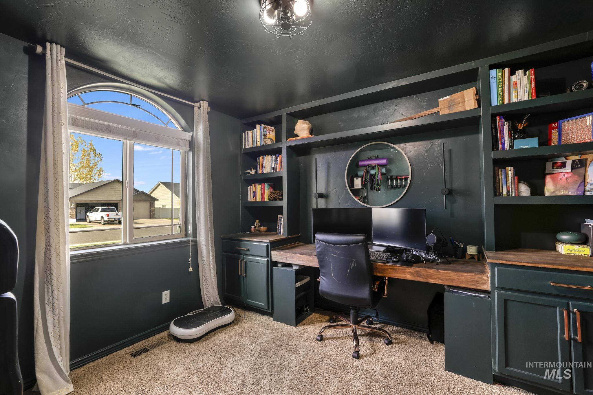 Office space with light carpet, a textured ceiling, and built in study area