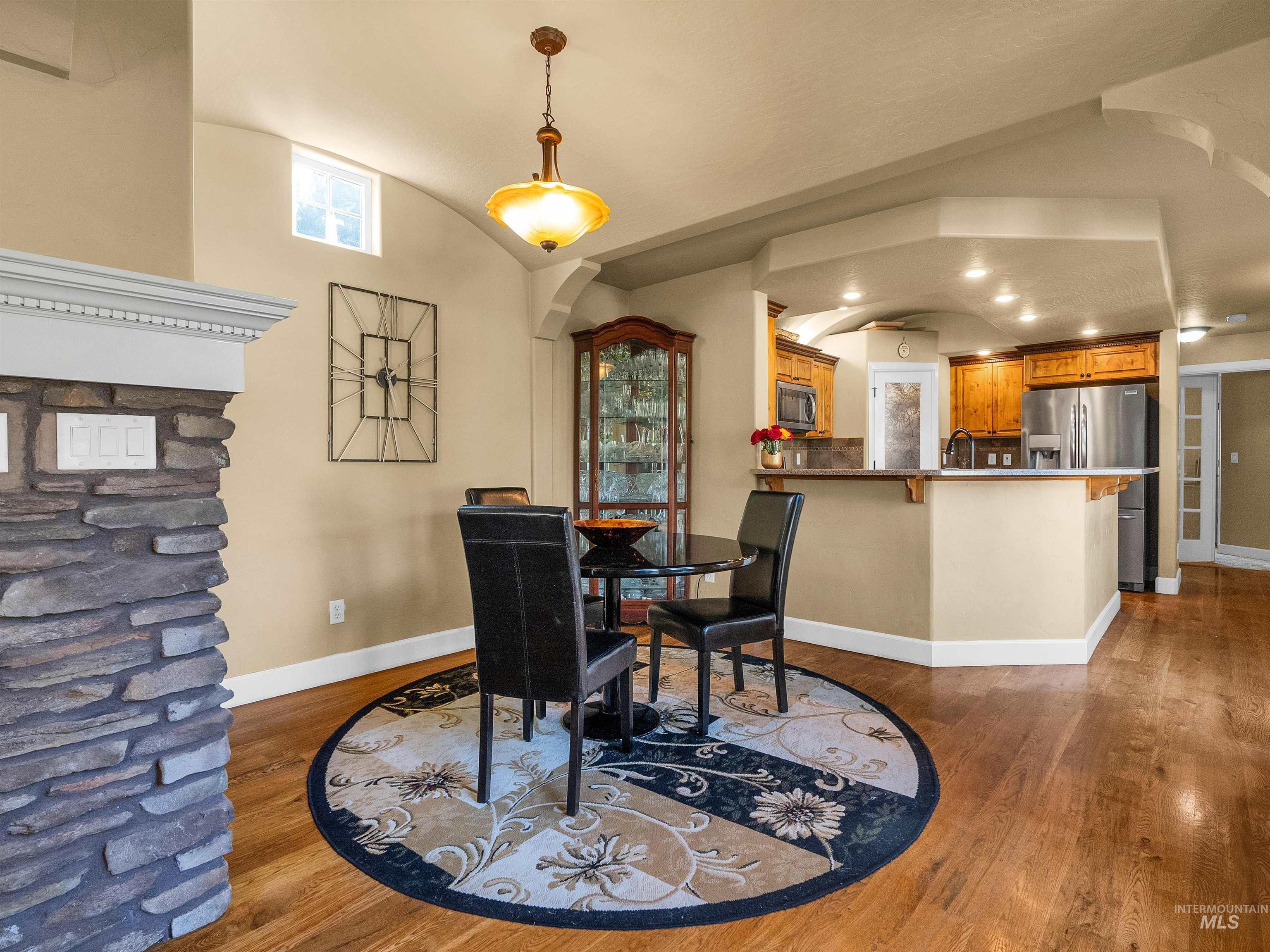 Dining space with vaulted ceiling, wood finished floors, and arched walkways