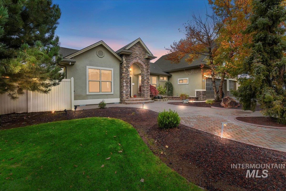 View of front of property with stucco siding, driveway, and stone siding