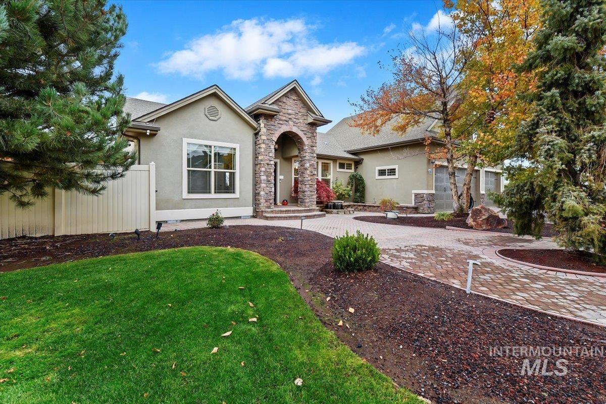 View of front facade with stucco siding, stone siding, and driveway