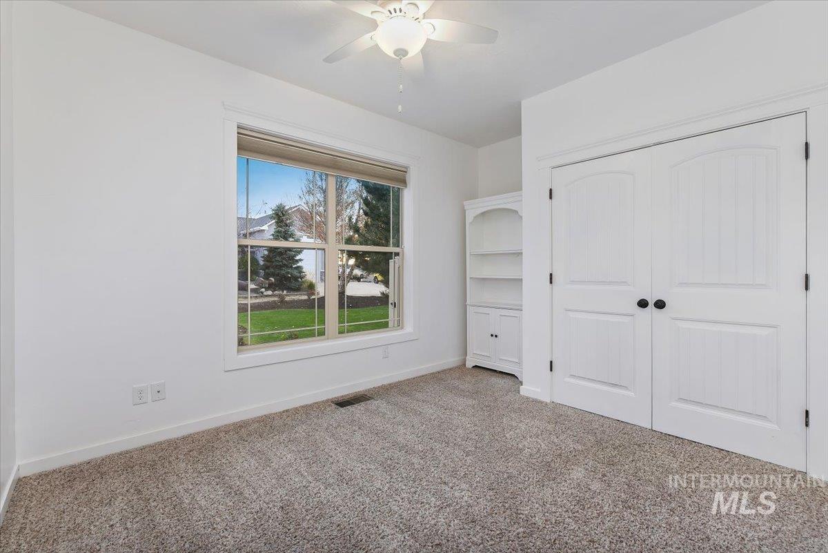 Unfurnished bedroom with carpet, a closet, and a ceiling fan