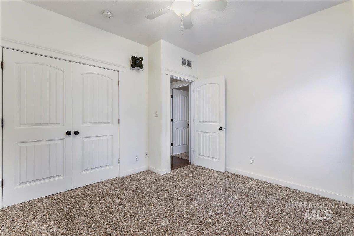 Unfurnished bedroom with a closet, carpet, and a ceiling fan