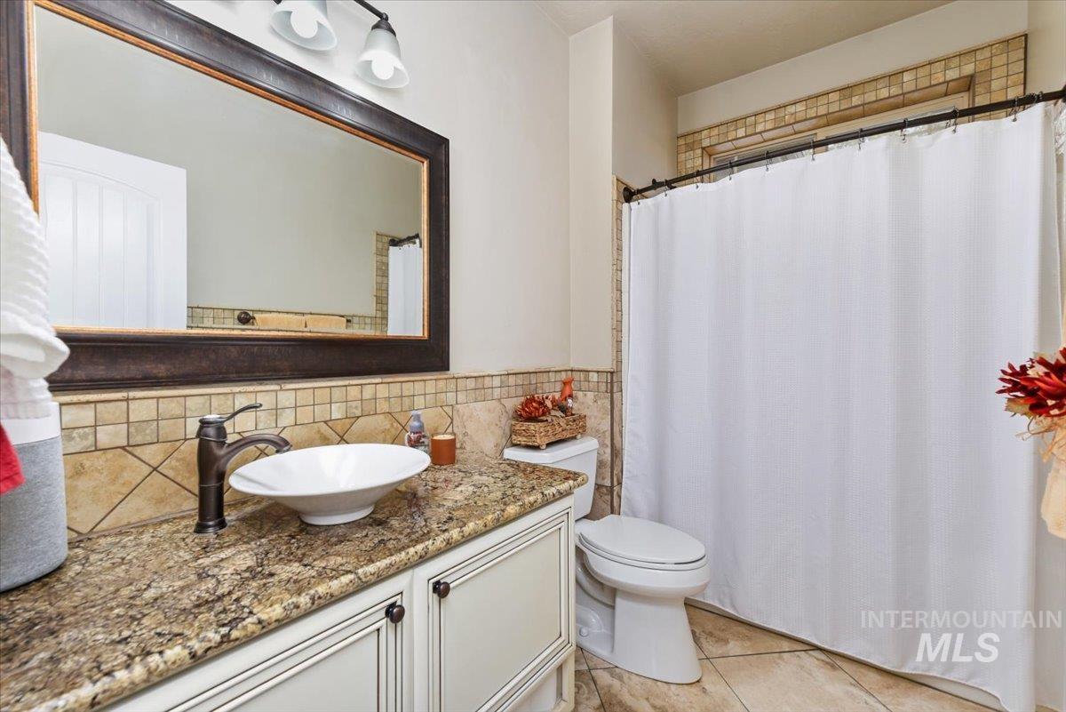 Full bath with a compo tub shower vanity, light tile patterned floors, and tile walls