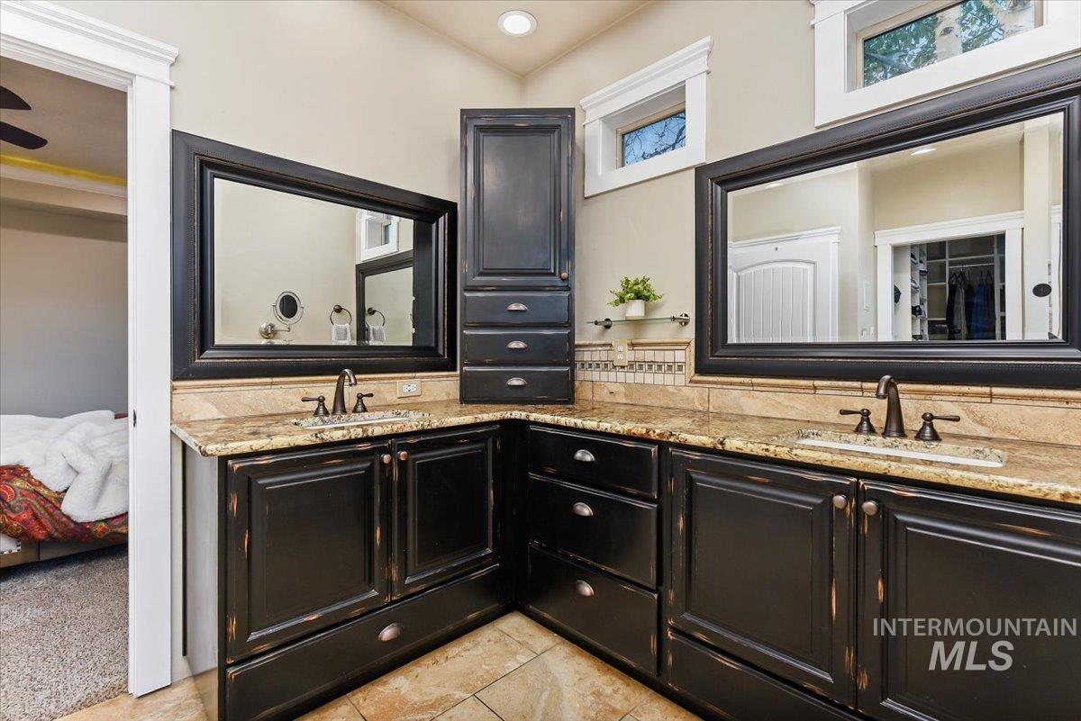 Full bathroom featuring ensuite bath, double vanity, light tile patterned flooring, and a walk in closet