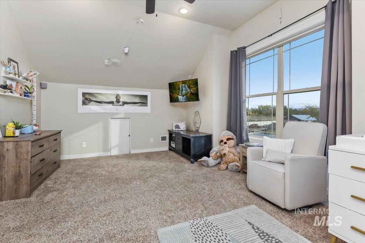 Living area with lofted ceiling, light colored carpet, and a ceiling fan