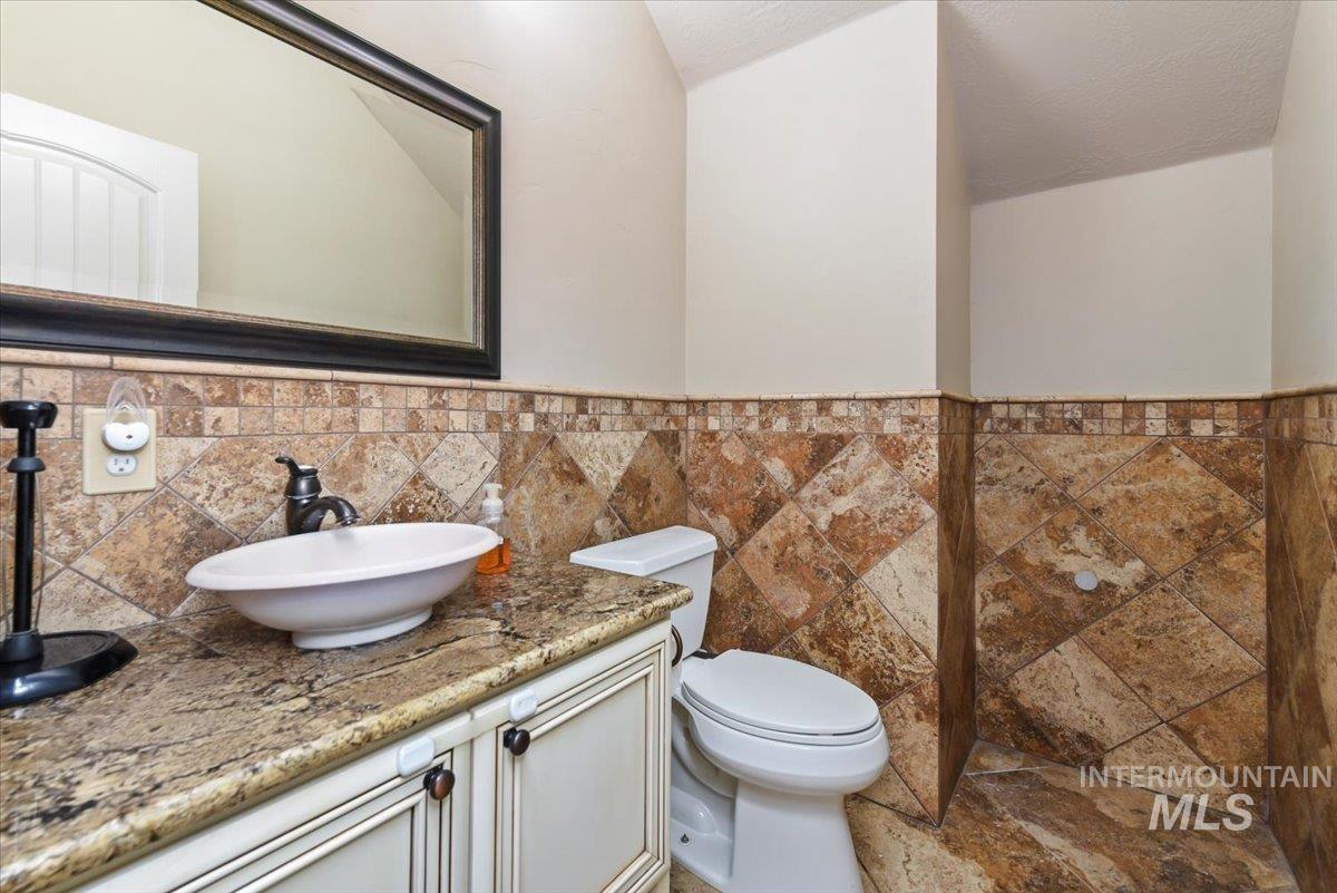Half bathroom with vanity, tile walls, wainscoting, and a textured ceiling